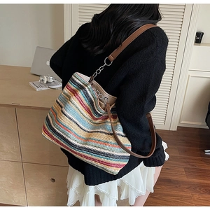 Dettaglio della borsa tote tessuta a righe colorate con tracolla in pelle marrone e catena