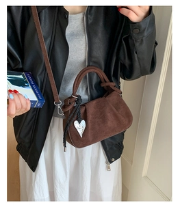Detail of vintage brown suede bucket bag with heart pendant and braided handle detail