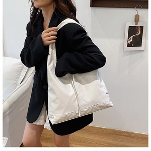 Minimalist beige tote bag with pleated texture shown as an over-the-shoulder casual look
