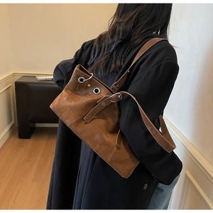 Detail of vintage brown leather tote bag featuring large eyelets and adjustable strap