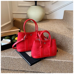 Detail view of two red suede tote bags with metal rivets on a stylish indoor staircase