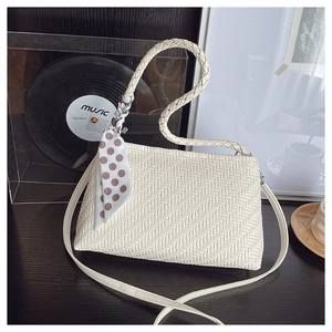 Detail of white woven texture handbag with polka dot scarf and braided top handle