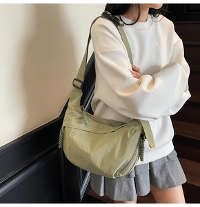 Dettaglio della borsa dumpling verde chiaro con tracolla ampia e tirazip intrecciato
