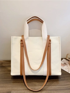 Vintage canvas tote bag with brown leather handles and adjustable shoulder strap