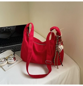 Detail of red canvas hobo tote bag featuring a zip closure and coffee cup charm