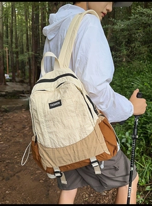 Close-up of lightweight tricolor patchwork outdoor backpack on a hiking forest trail