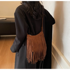 Close-up of brown suede fringe crossbody bag with boho style tassels on a black coat