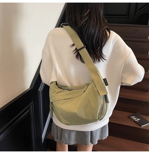 Dettaglio della borsa a tracolla a mezzaluna verde con zip intrecciata e logo del brand