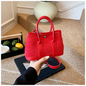 Detail of red suede patchwork tote bag with silver circular metal buckle and strap