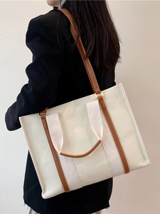 Minimalist canvas tote bag with brown leather straps shown on model for office style