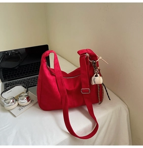 Detail of red canvas crossbody tote bag with adjustable strap and coffee cup charm decoration