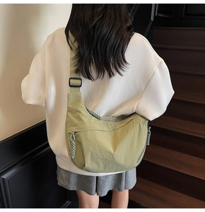 Modella che indossa borsa a mezzaluna in nylon verde avocado con dettaglio zip intrecciata
