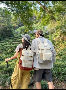 Outdoor lifestyle shot of a large-capacity canvas backpack in cream and brown accents