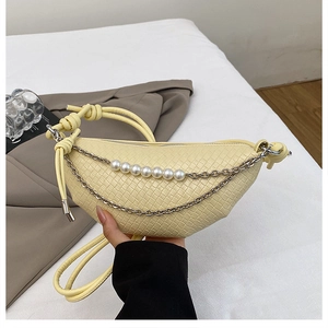 Détail du sac croissant tissé avec chaînes argentées décoratives et perles blanches