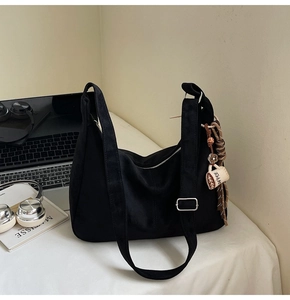 Detail of black canvas half-moon tote bag with coffee-themed charm on a desk