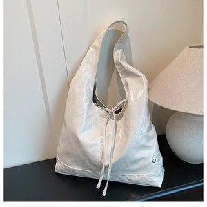 Detail of white glossy pleated leather tote bag with heart logo and drawstring closure