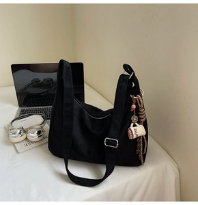 Detail of black canvas tote bag with adjustable strap and decorative coffee cup pendant