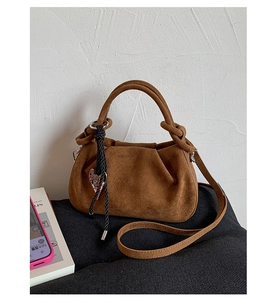 Detail of brown suede pleated shoulder bag with soft texture and metallic charm