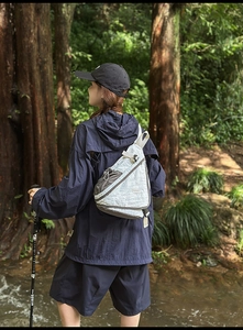Outdoor crossbody bag in white and grey fabric shown during a forest hiking session