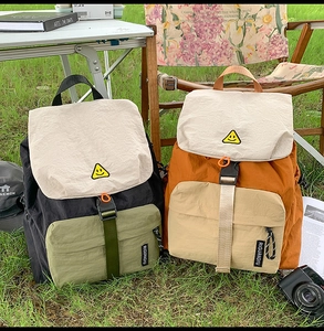 Detailed view of large-capacity nylon backpacks with smiley face patch in a camping setting