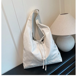 Macro detail of the pearlescent white faux leather and drawstring on this large hobo bag