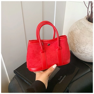 Detail of red suede patchwork tote bag with metallic snap button and minimalist design