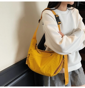 Dettaglio di una borsa a tracolla a mezzaluna in nylon giallo con ampia cinghia