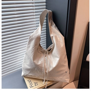 Detail of cream pleated tote bag with bow accent and small heart metallic buckle