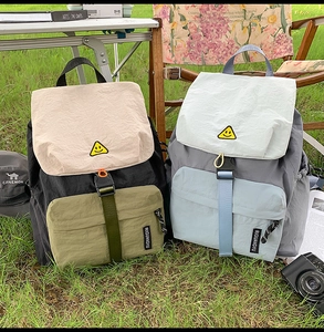 Close-up of color-block nylon backpacks with contrast straps in an outdoor camp setting