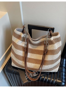 Grande borsa tote intrecciata a righe con pelle marrone e catena in metallo su valigia