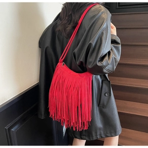 Detail of red fringe suede shoulder bag with tassels shown on a model in a leather jacket