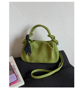Detail of green suede dumpling bag with pleated texture and heart pendant