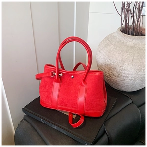 Detail view of red suede and leather tote bag featuring a metallic ring buckle accent