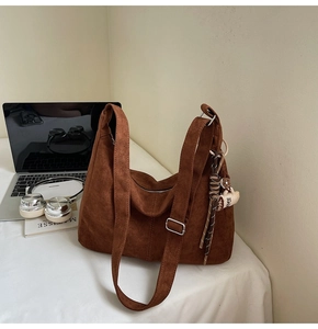 Close-up of brown suede hobo bag with adjustable strap and decorative coffee tassel