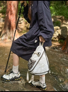 Close-up of waterproof outdoor crossbody bag with tear-resistant nylon in a forest setting