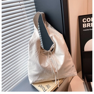 Close-up of a white tote bag featuring textured fabric and a delicate bow detail