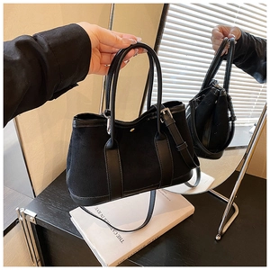 Detail showing black suede tote bag with leather straps and detachable long shoulder strap