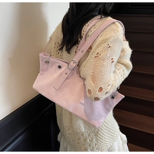 Side view of pink suede tote bag with eyelet details worn by a model on stairs