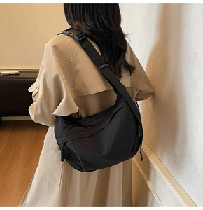Borsa a tracolla a mezzaluna in nylon nero con ampia tracolla regolabile indossata