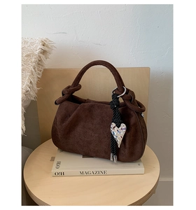 Close-up of a vintage dark brown matte bucket bag with a knotted top handle on a table