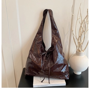 Detail view of large burgundy tote bag with pleated patent leather and bow decoration