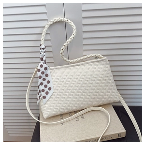 Detail of cream woven shoulder bag featuring a polka dot silk scarf on the top handle