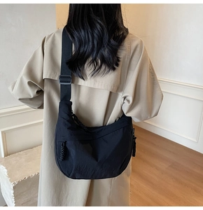 Dettaglio della borsa a mezzaluna in nylon nero con tracolla larga e cordini laterali