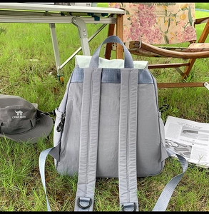 Rear view of grey waterproof nylon backpack showing padded straps on outdoor grass