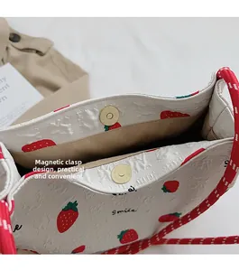 Detail of magnetic clasp closure and interior pocket on strawberry print bucket bag