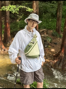 Waterproof nylon crossbody bag showing adjustable buckle and webbing in forest setting