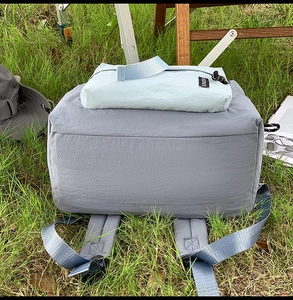 Close-up of grey and blue nylon backpack on grass for outdoor travel and leisure