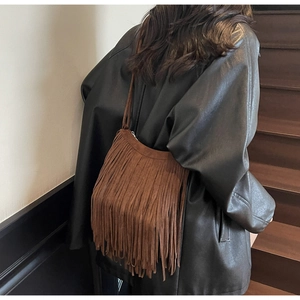 Close-up of brown suede tassel crossbody bag with bohemian fringes and long shoulder strap