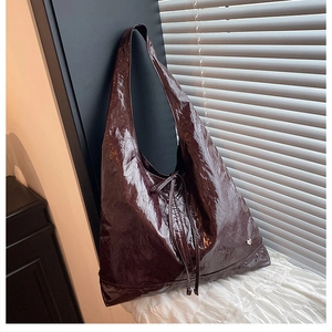 Macro detail of glossy crinkled burgundy tote bag with metallic heart rivet