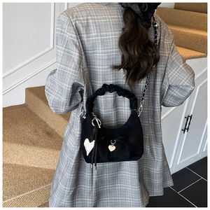 Detail of black crescent suede bag with pleated handle and golden heart charm pendant